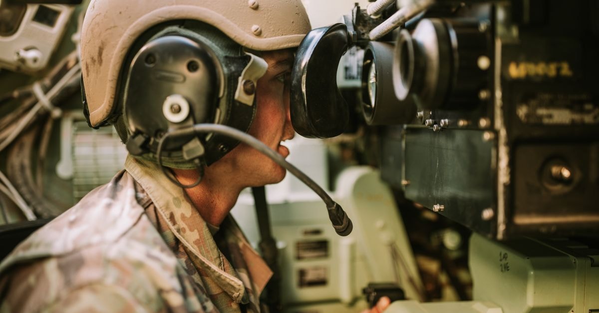 A soldier in uniform operates military equipment inside a vehicle, showcasing modern military technology.