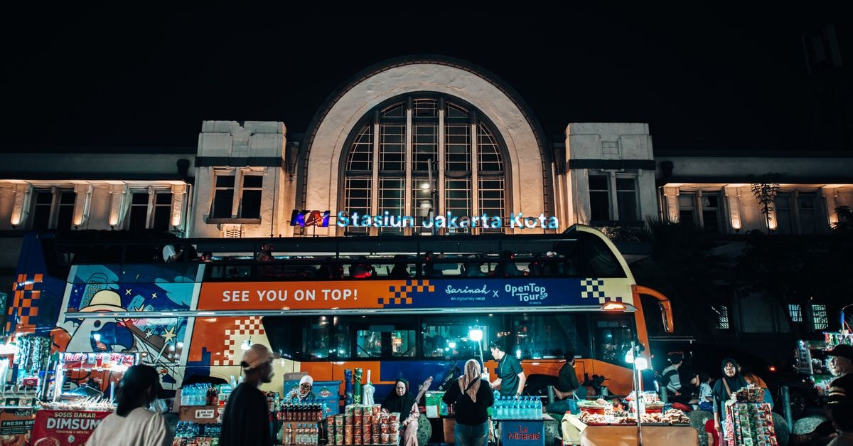 Jakarta Kota Station 繁忙的夜間市集景象，生動的雙層巴士與街頭攤販盡在其中。