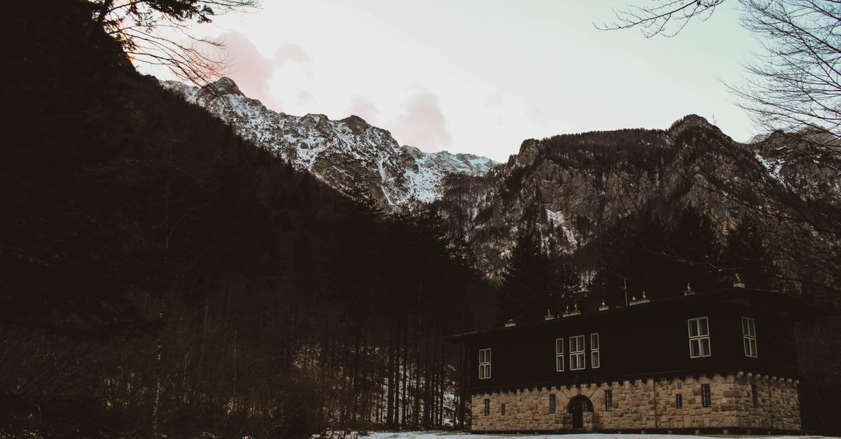 Idyllic winter landscape featuring a house against Kamniška Bistrica mountains in Slovenia.