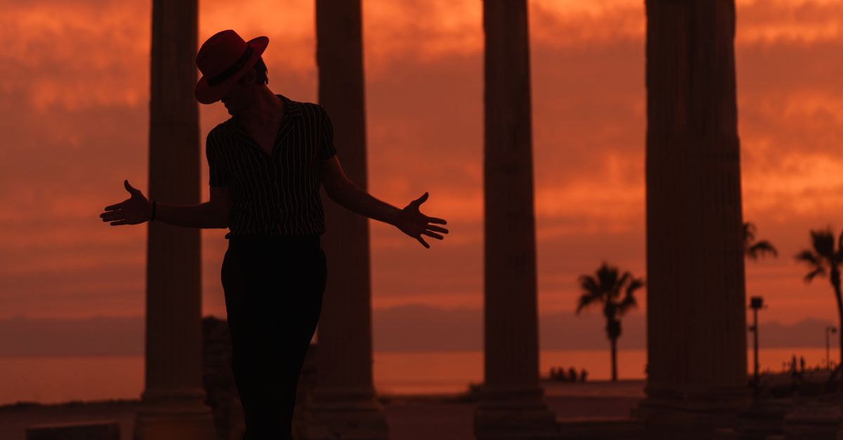 The Odyssey hits $346 million in opening week as Michael tops 2026 global box office Dramatic silhouette of a performer in a red hat against ancient columns at sunset.