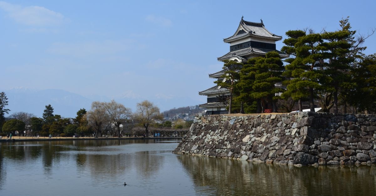 Matsue Travel Guide: Castles, Literary Heritage and Lakeside Calm Scenic view of historic Matsumoto Castle by a serene lake surrounded by nature.