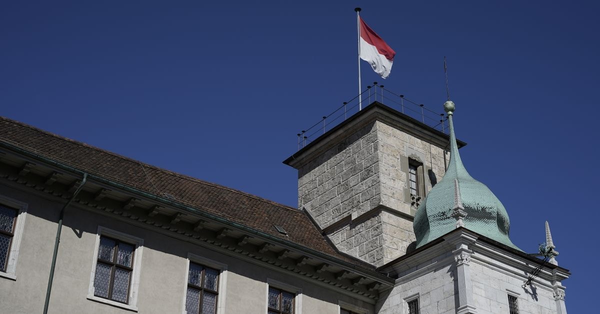 La Couronne in Solothurn: Switzerland's Second-Oldest Hotel in the Old Town Low angle view of a historic tower with a flag against a clear blue sky in Solothurn, Switzerland.