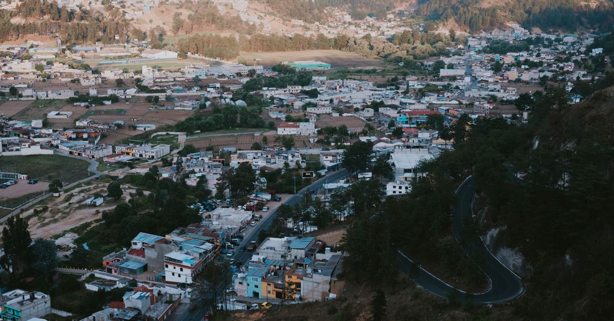 Aerial view of a picturesque mountain town nestled in lush greenery and rugged terrain.