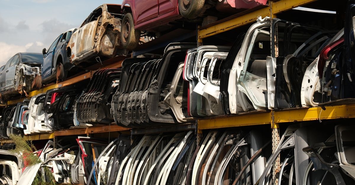 Rows of car doors stacked in a junkyard under a clear sky.