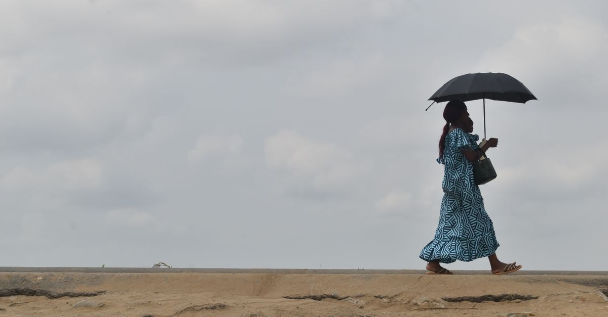 Ouésso Travel Guide: Into the Sangha River Heart of Congo A woman walks with an umbrella on a cloudy day in République du Congo.