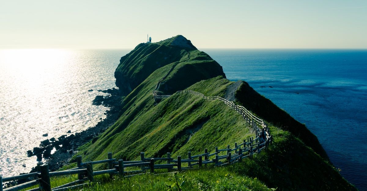 A Quiet Aomori Travel Guide: Northern Japan’s Calm Coast Stunning view of Cape Kamui with lush green cliffs and a vibrant blue ocean in Hokkaido, Japan.