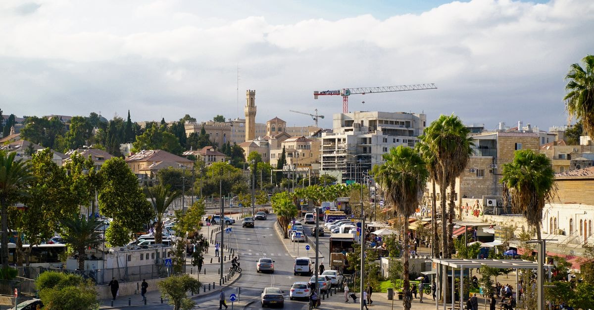 Dan Carmel, Haifa — Panoramic Mount Carmel Stay Near the Baha'i Gardens View of Jerusalem streets with historic buildings and palm trees under a clear blue sky.