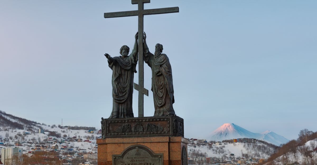 Petropavlovsk-Kamchatskiy Travel Guide: Edge of the Pacific Statue of Apostles Peter and Paul holding a cross in snowy Kamchatka with mountains in the background.
