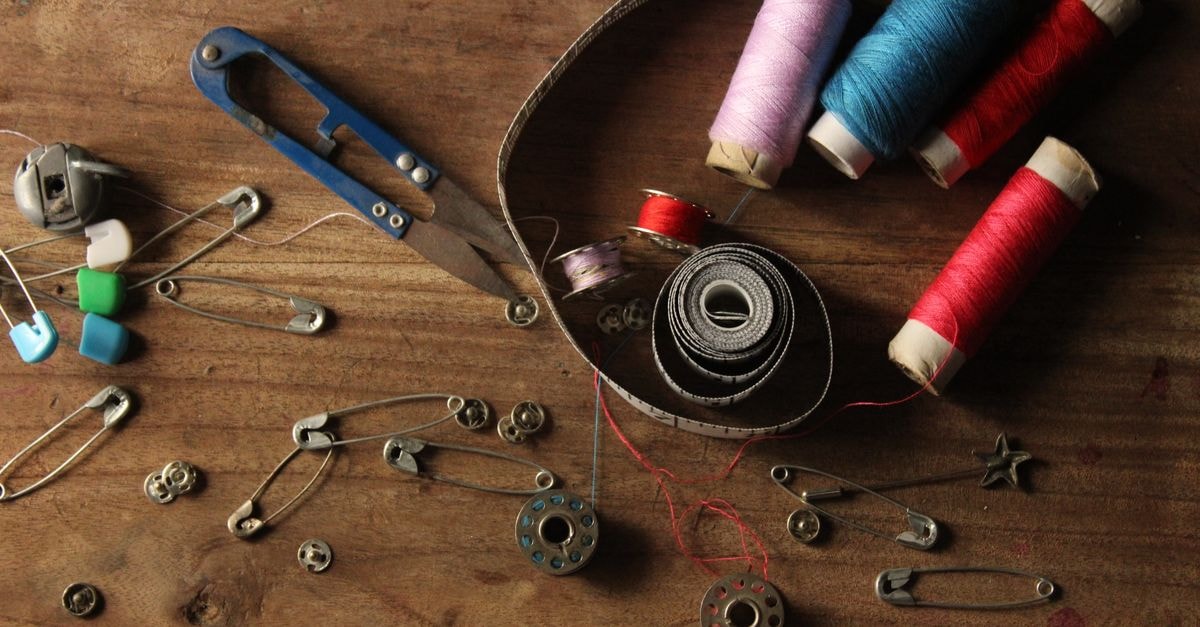 A vibrant collection of sewing supplies including threads, scissors, pins, and tape on a wooden surface.
