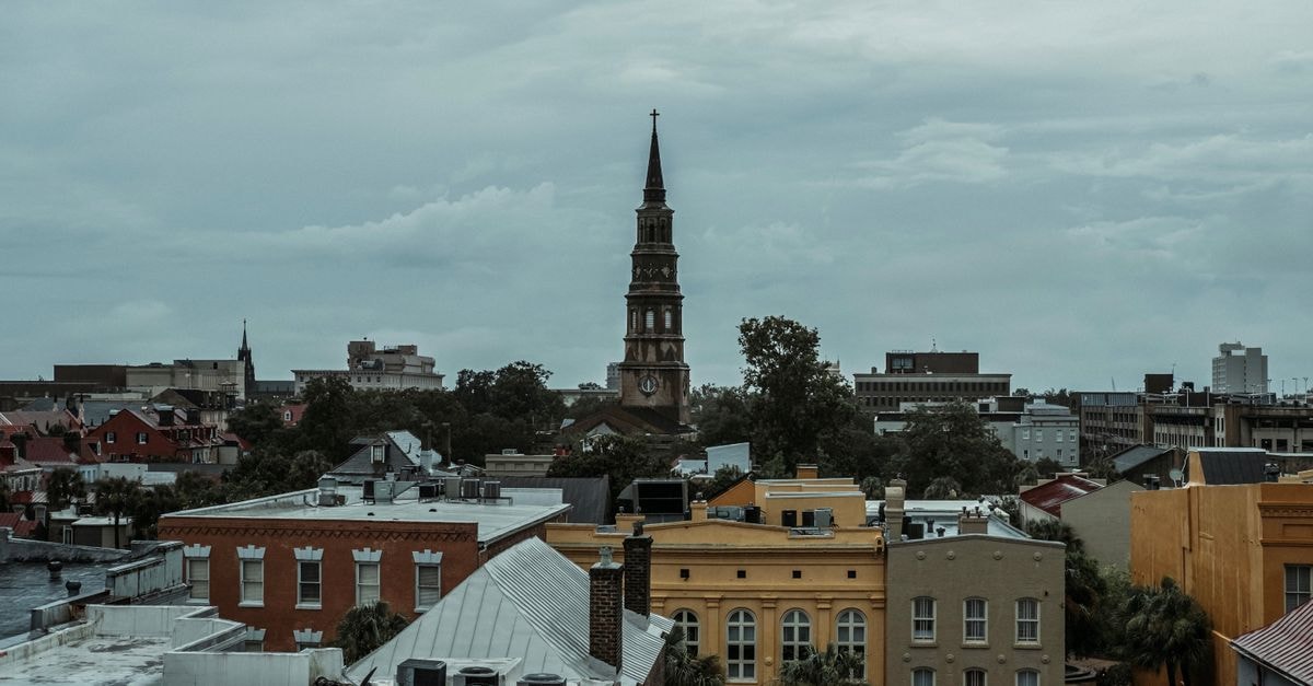 A picturesque view of Charleston, SC, featuring a historic church tower amidst vibrant buildings.