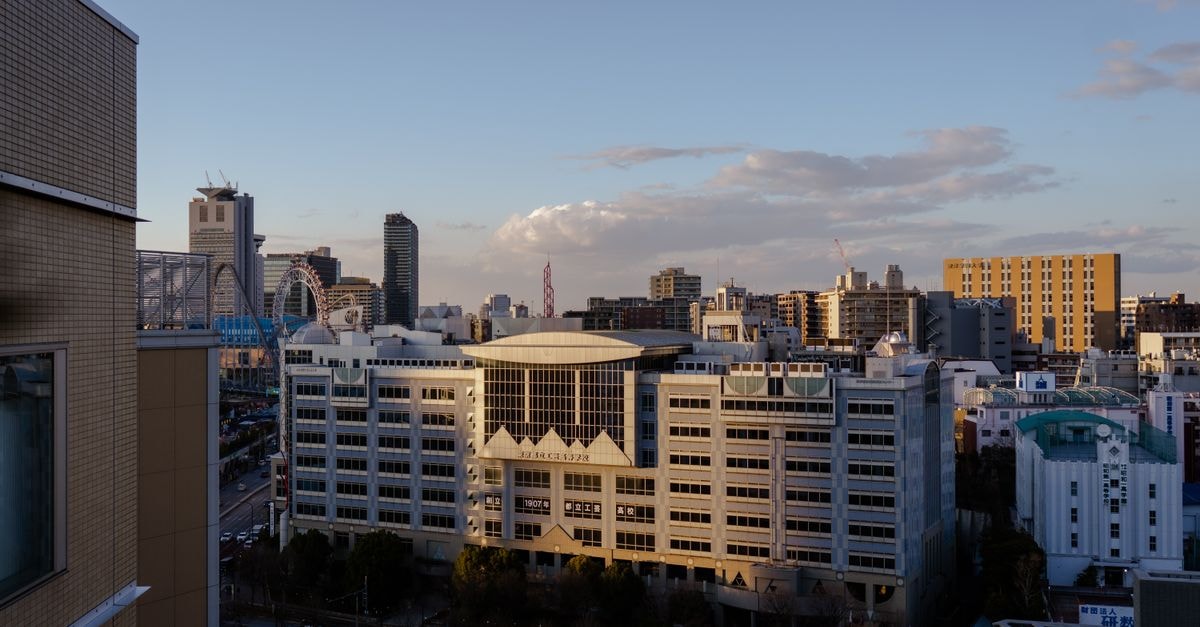 Hisai Green Hotel, Tsu — A Compact Stay in the Hisai-Ninomachi District Aerial view of a modern city skyline with contemporary architecture at dusk.