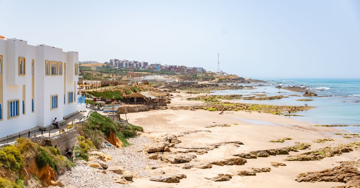 Sidi Bouzid Travel Guide: Planning Tips, Costs and Things to Do Beautiful coastal view featuring white buildings, sandy beach, and rocky shoreline under a clear blue sky.