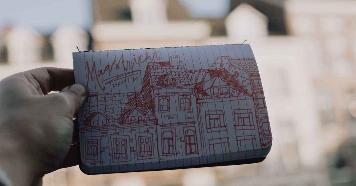 Things to Do in Maastricht in July 2026: André Rieu Weekends, Weather and Local Food A hand holds a sketch of Maastricht architecture outdoors with blurred background.
