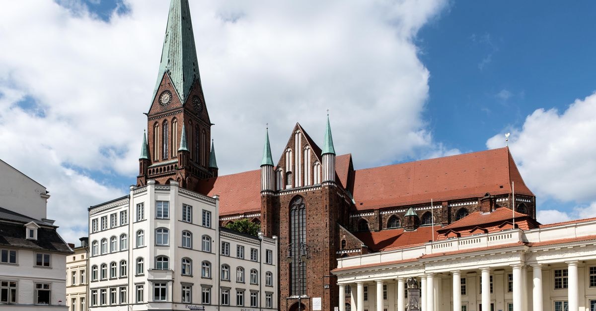 View of Schwerin Cathedral and Market Square in Germany with historic architecture under a blue sky.