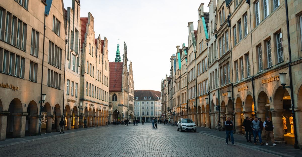Hotel Martinihof, Münster: 120 Years of Family-Run Tradition Charming street view of the Prinzipalmarkt in Münster, Germany at dusk with historic architecture.