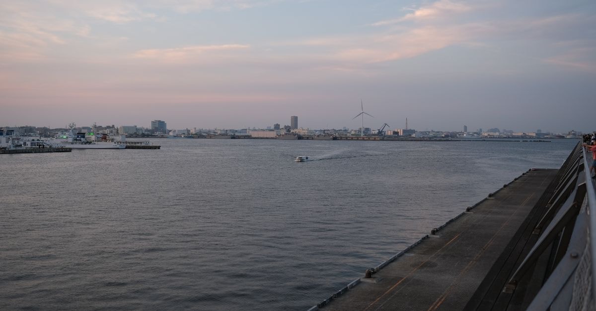 Yokohama travel guide: a port city's quiet rhythm Tranquil view of a motorboat on Yokohama bay with city skyline at dusk.