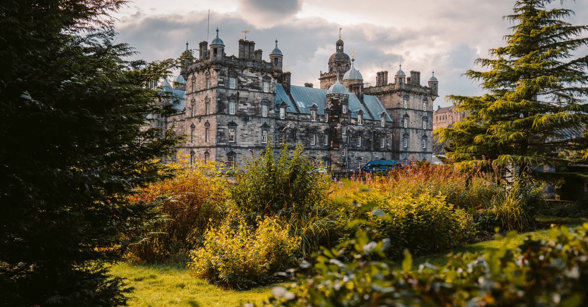 A picturesque view of an ancient castle surrounded by vibrant greenery under a cloudy sky.
