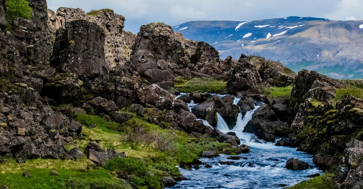 A flowing mountain stream surrounded by rocky terrain and greenery in a picturesque landscape.