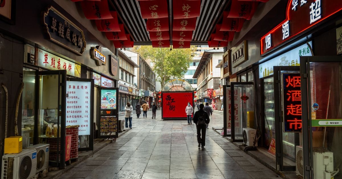 Vibrant shopping street in Luoyang, China with red banners and local shops.