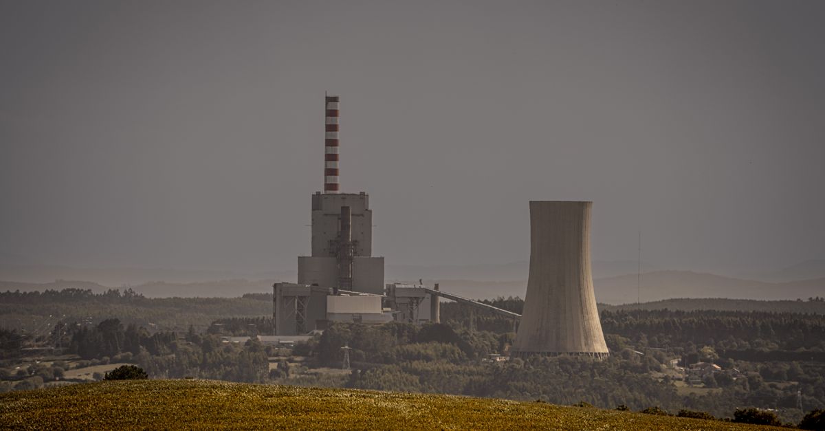 Distant view of a power plant with cooling towers amidst a vast landscape, illustrating energy production.