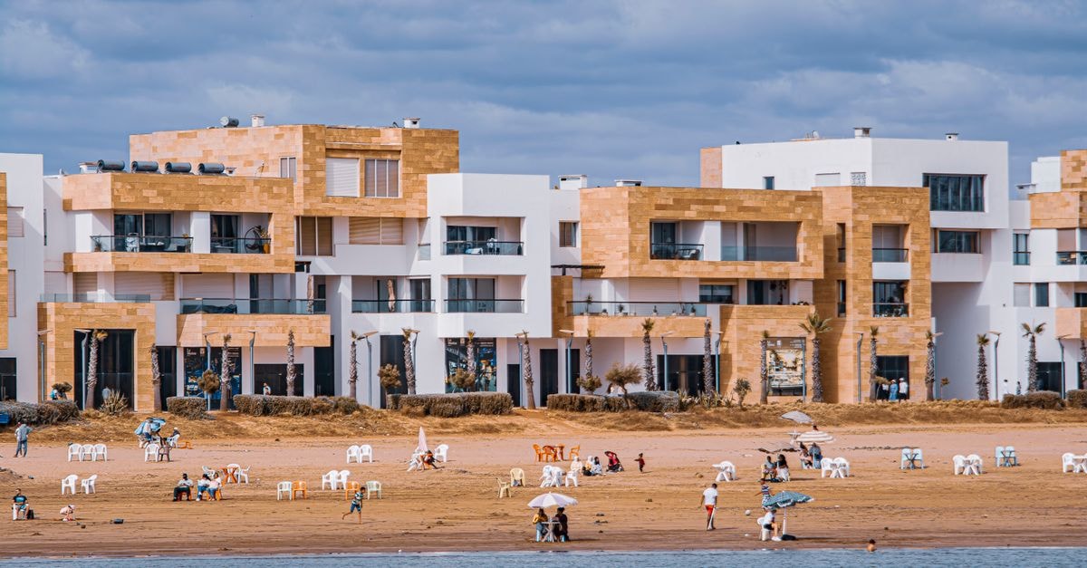 Sidi Bel Abbes Travel Guide: Planning Tips, Costs and Things to Do Coastal view of modern apartments and people enjoying a peaceful day at the beach.
