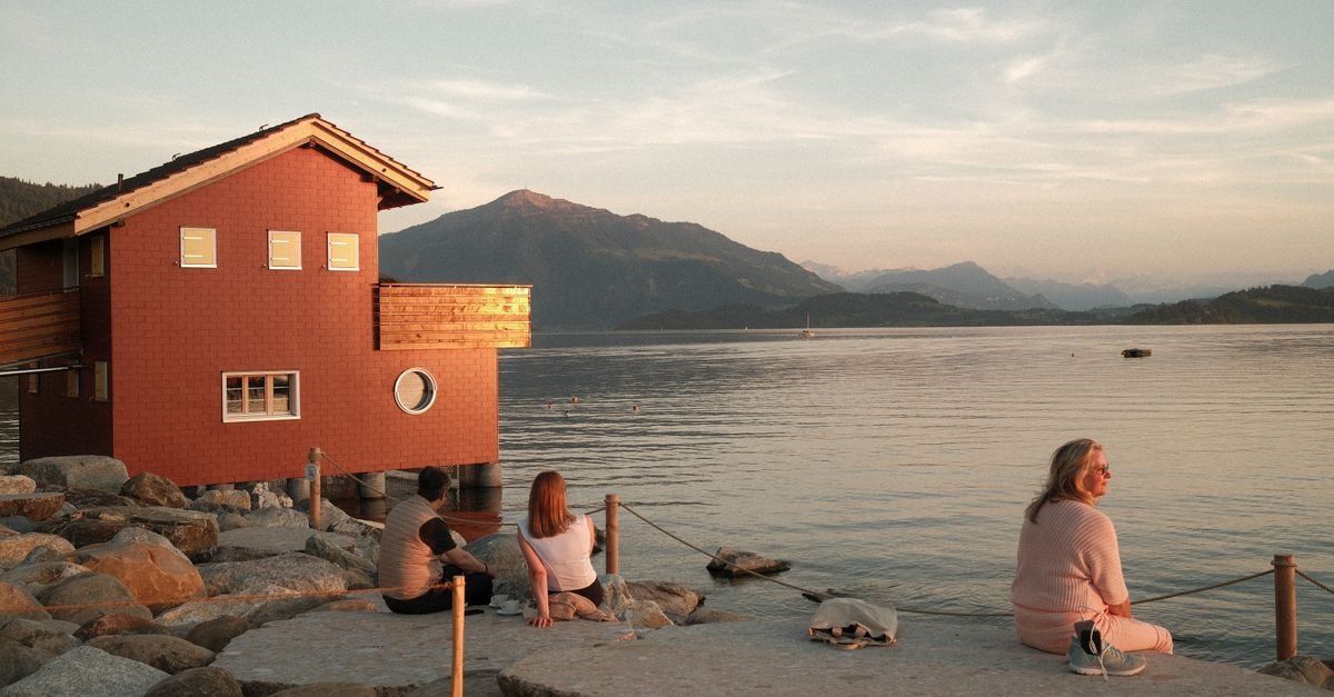 Sarnen Travel Guide: A Quiet Obwalden Base for Lake Days and Alpine Excursions Tranquil scene in Zug, Switzerland, with people enjoying sunset by the lake, framed by mountains.