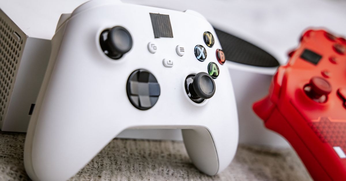 A close-up shot of white and red gaming controllers on a textured surface, highlighting modern gaming technology.