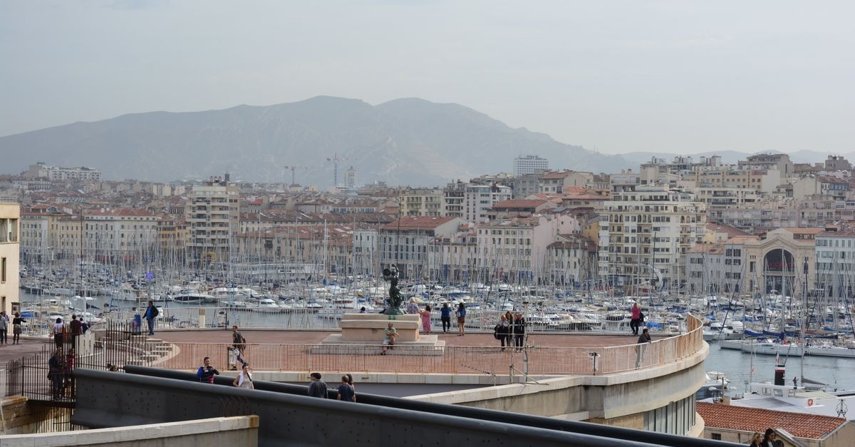Marseille travel guide: harbor walks, tram rides, and easy French bites A clear view of Marseille's Vieux Port and city skyline with people exploring the area.