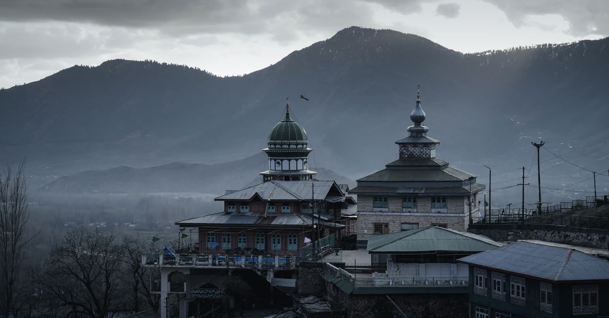 Jammu travel guide: temples, river views, and food culture A tranquil scene of the Aishmuqam shrine surrounded by majestic mountains at dusk.