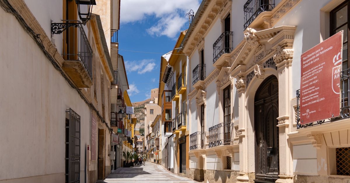 Murcia, Spain Travel Guide: Sun-Soaked Streets and Local Flavor Charming street view in Lorca, Spain showcasing colorful historic architecture under a bright blue sky.