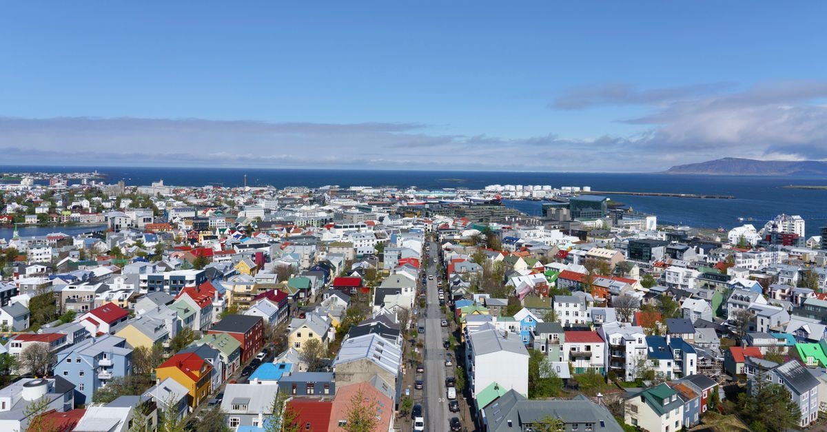 Vibrant aerial view of Reykjavik, Iceland, showcasing colorful rooftops and ocean backdrop under a clear sky.