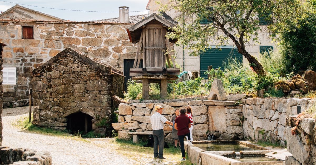 A Quiet Beja Travel Guide: Slow Days 's Alentejo A picturesque view of a historical village in Montalegre, Portugal featuring a traditional mill and rustic architecture.