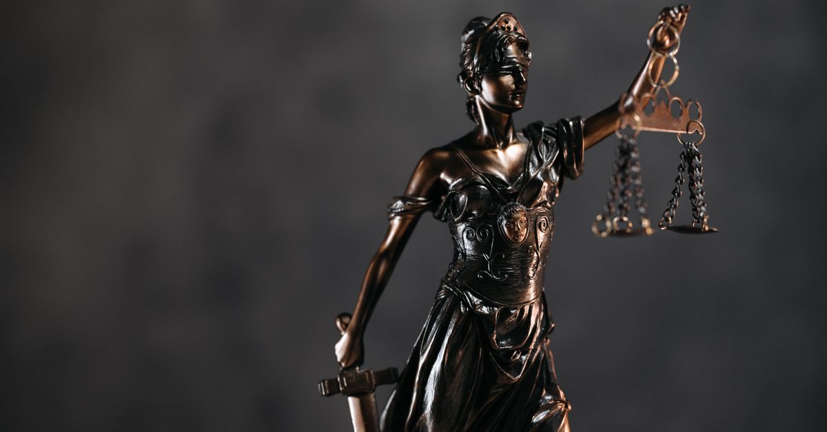 Detailed bronze Lady Justice statue with scales and sword against a dark background, symbolizing law and justice.