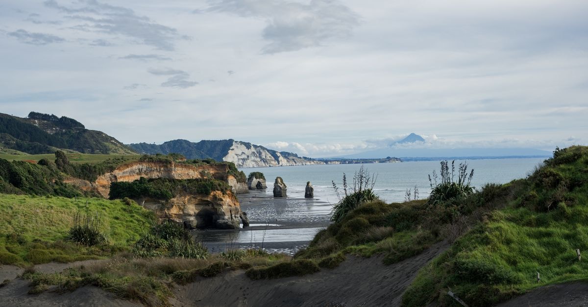 Serene landscape of New Zealand's Elephant Rock and Three Sisters with Mount Taranaki in the background.