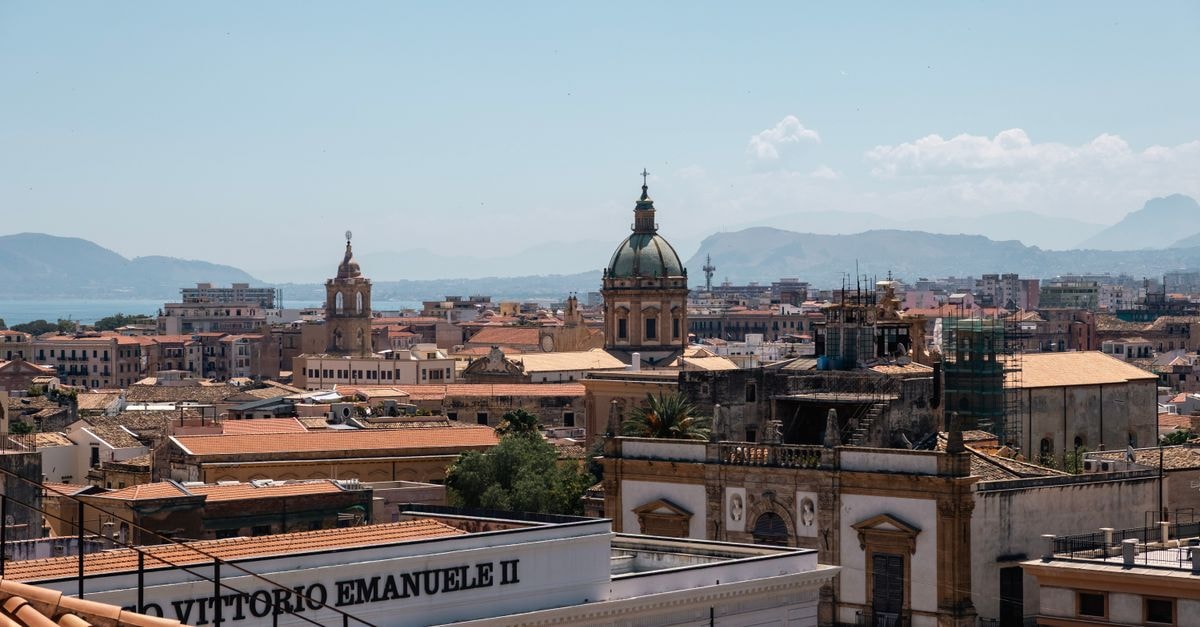 Hotel Cortese in Palermo: A Budget Stay Inside a 14th-Century Palazzo Captivating view of Palermo's historic architecture against a mountainous backdrop under a clear sky.