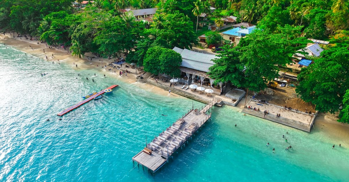 Stunning aerial shot of Manokwari beach, featuring clear turquoise waters and lush greenery.