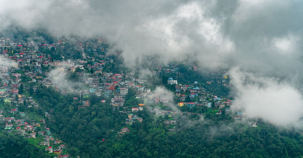 Darjeeling Travel Guide: Getting Around and Heritage Highlights A scenic view of Darjeeling's colorful hillside under clouds.