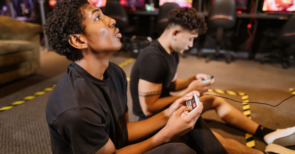 Xbox grants free PC Ubisoft copies to console owners as CTO details major outage Two teenagers deeply engaged in a video gaming session at an indoor arcade.