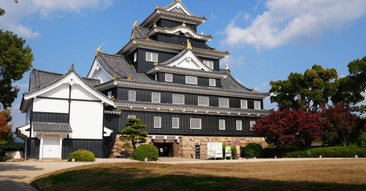 Kakogawa Travel Guide: Things to Do, Eat, and Discover Okayama Castle with traditional architecture and colorful autumn foliage under clear sky.
