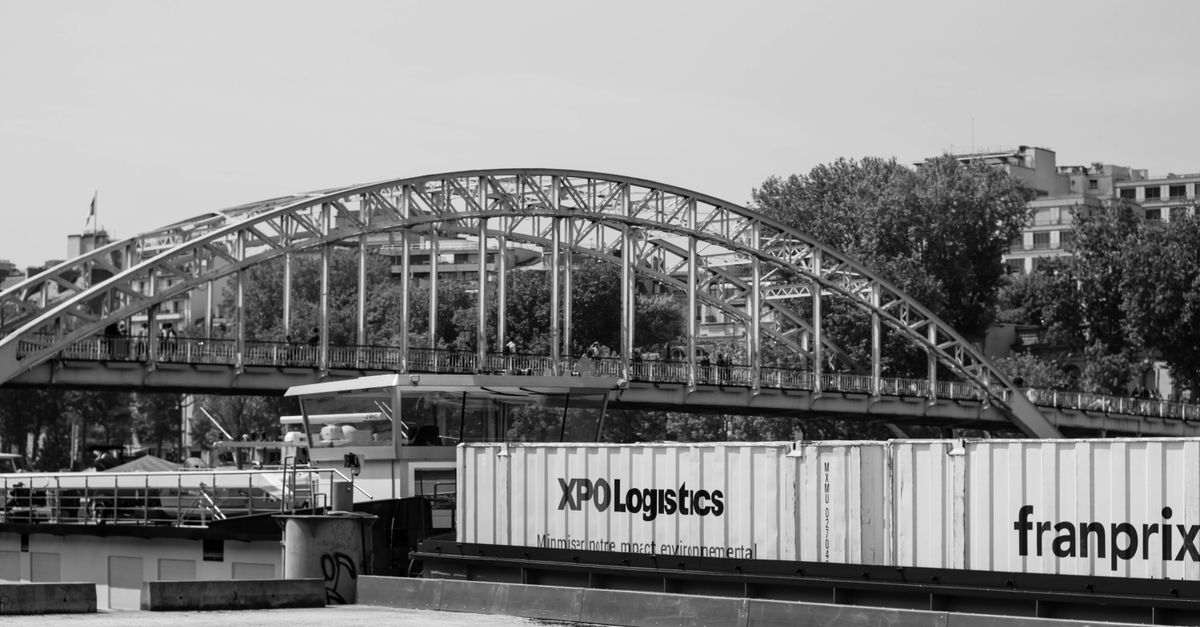 A black and white photo of a Parisian bridge over the Seine with shipping containers.