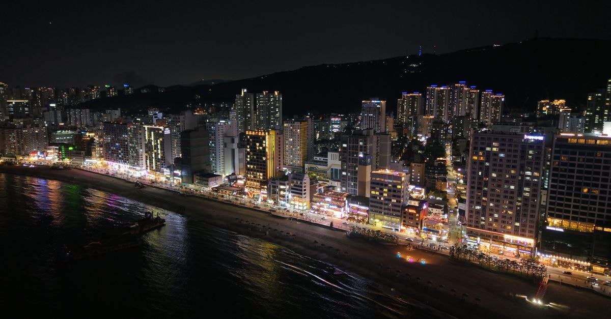 Backpacker's Home in Seogwipo: 98-Room Base Near Jeju World Cup Stadium A stunning nighttime view of Busan's illuminated skyline and coastline in South Korea.
