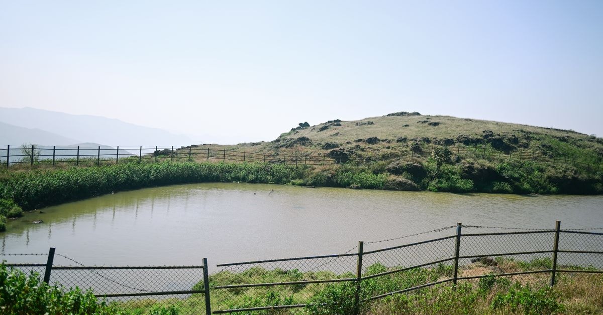 Chikkamagaluru, Chikkamagaluru — A Coffee-Gateway Stay in Karnataka's Western Ghats Serene landscape of a pond surrounded by hills and a fence in Chikkamagaluru, India.