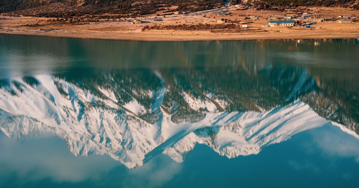 Shigatse, Tibet: A Quiet Travel Guide for First-Time Visitors Snowcapped mountains beautifully mirrored in calm lake reflecting clear sky.