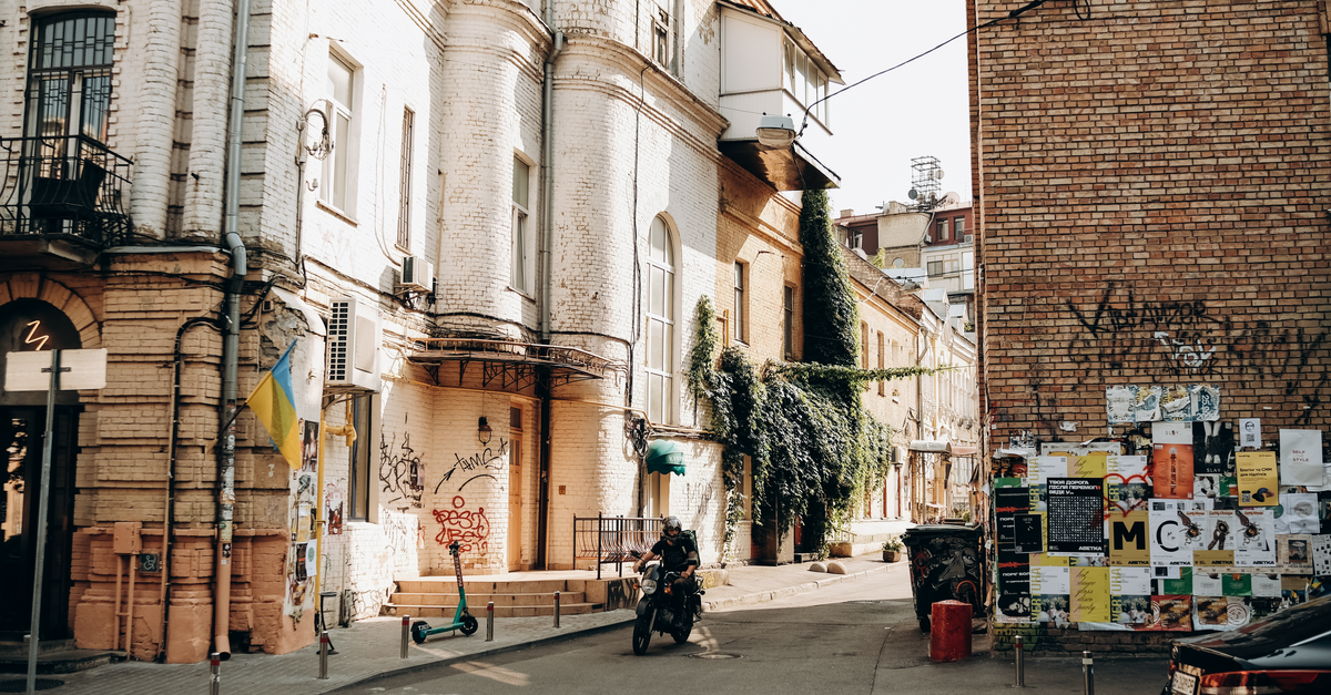 Sumy Travel Guide: Discovering a Quiet Northeastern Ukrainian City A vibrant street view in Kyiv featuring a biker, historical architecture, and urban art.