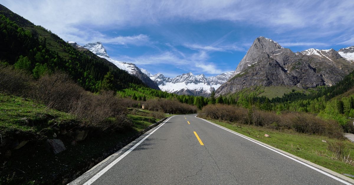 Guangyuan Travel Guide: Planning a Practical Trip Through Northern Sichuan A winding road leading through a stunning mountainous landscape under a vibrant blue sky.