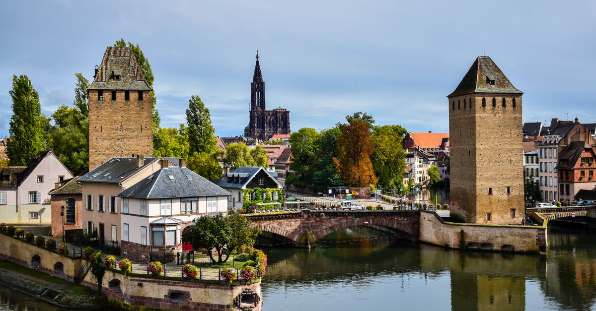 A scenic view of Strasbourg featuring Ponts Couverts and the cathedral in the background.