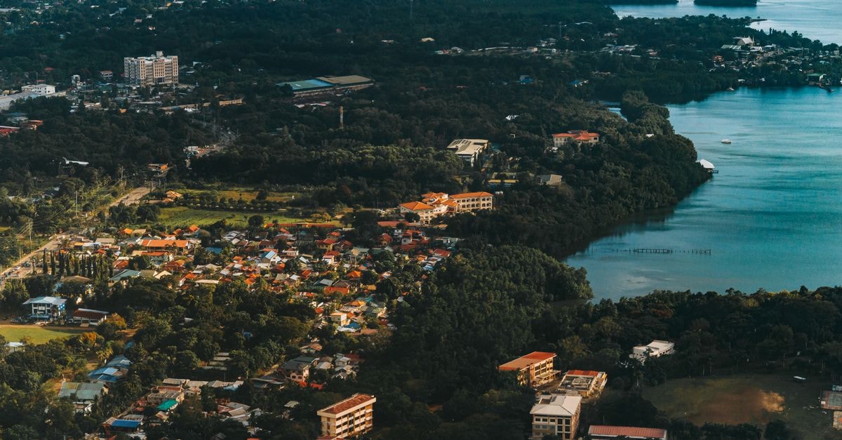 Tinapa Lakeside Hotel, Calabar: Lake-View Stay Inside the Tinapa Free Trade Zone Aerial view of a vibrant coastal city bordered by a tranquil lake and dense forest.