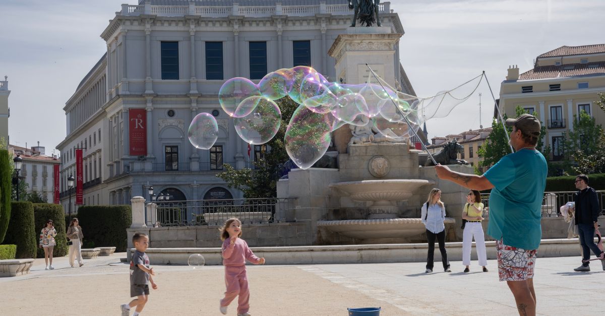 Joyful children playing with bubbles in front of Teatro Real, Madrid.
