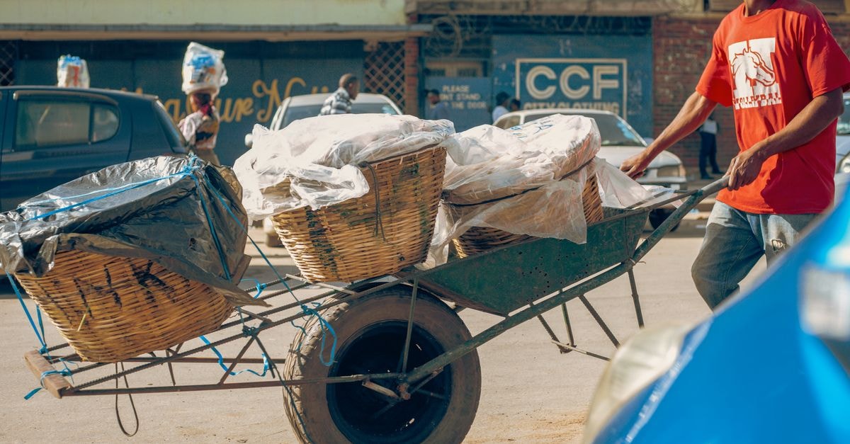 Mansa Travel Guide: Zambia's Quiet Luapula Capital A man in red shirt pushes a wheelbarrow with baskets on a bustling Lusaka street.