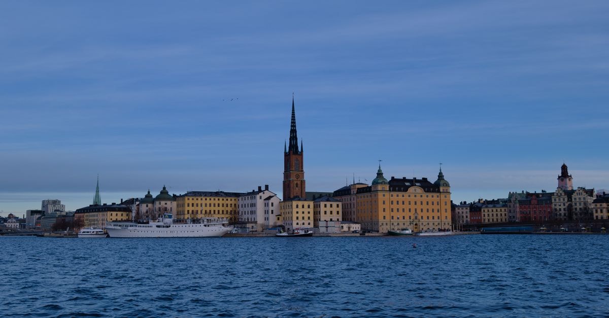 Stockholm Travel Guide: What to Know Before You Go Skyline of Stockholm with historic architecture reflecting on water under a clear sky.